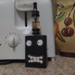 My VMU PV (TTTELiquids.com) with the MAP Tank mod (CloudsOfVapor.com) filled with Freedom Juice (HaloCigs.com), a shorty 510 Delrin plastic drip tip (ElectroNicStix.com), two protected 14500 Trustfire batteries (MadVapes.com), and inanimate character stickers (ThinkGeek.com).