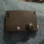 Front of the mod with the black button and the voltage adjustment dial.