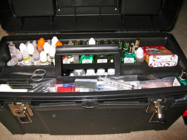 Here we have smaller bottles of juice on the top half, and the Hello Kitty bandaid tin holding attys that need cleaning.  The lower part holds a scissors, clean attys on the left, screwdrivers and assorted syringes/pipettes, and business cards.