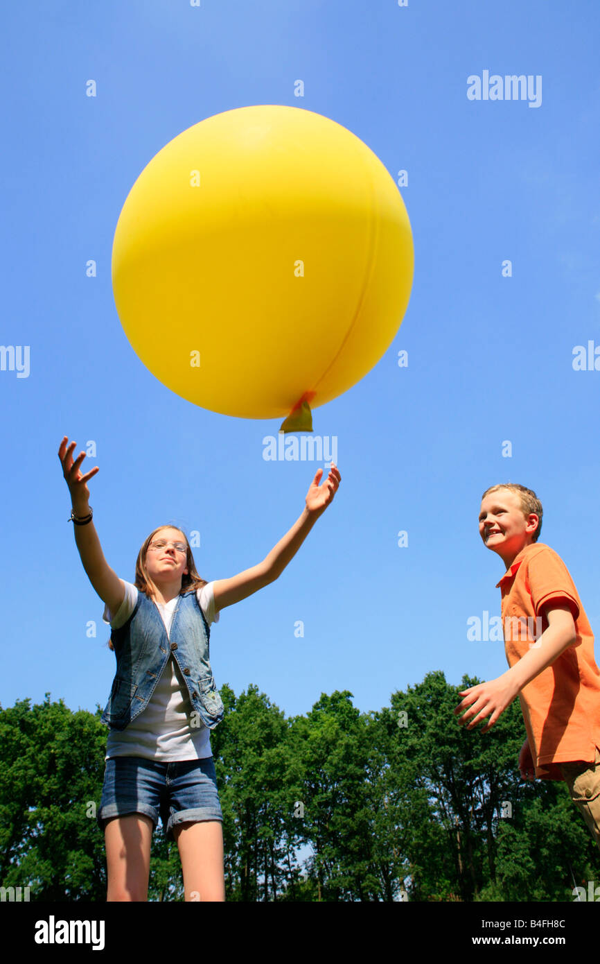 boy-and-girl-playing-with-a-big-yellow-balloon-B4FH8C.jpg