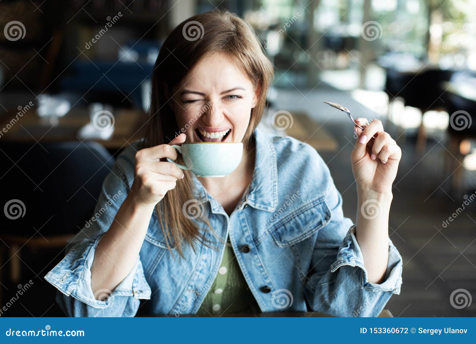 young-woman-drinking-coffee-smiling-winking-cafe-153360672.jpg