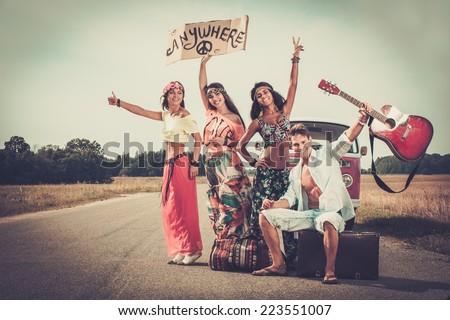 stock-photo-multi-ethnic-hippie-hitchhikers-with-guitar-and-luggage-on-a-road-223551007.jpg