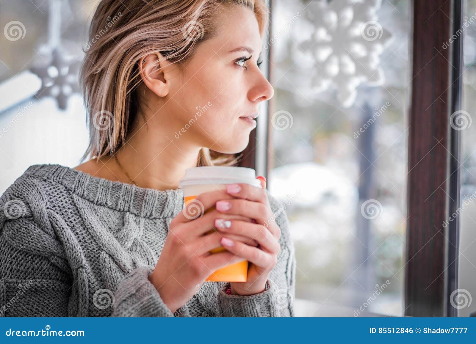 woman-drinking-coffee-looking-out-window-close-up-85512846.jpg